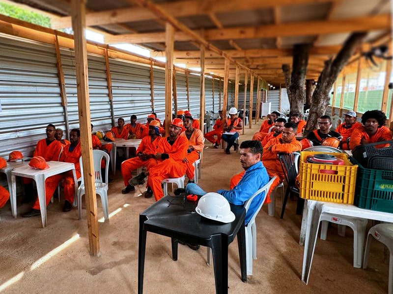 Trabalhadores uniformizados assistem a uma palestra em capacitação profissional no método parede de concreto.